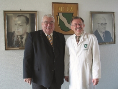 Präsident Meise, Dr. C.-L. Riedel vor dem MLUA-Wappen